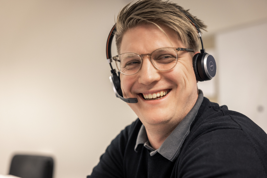 hymyilevä CERTEGOn asiakaspalvelija puhuu headset päässään