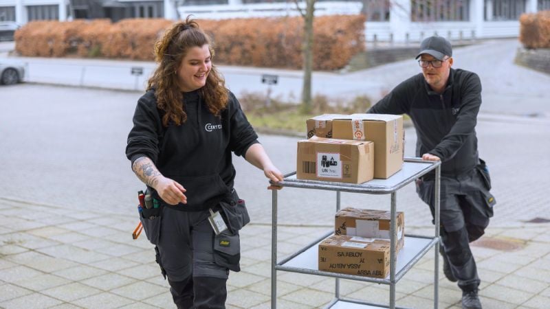 Certegon työntekijät työntää pakettikärryä - Vastuullisuus tavarantoimittajien kanssa.